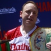乔伊·切斯特纳特 (Joey Chestnut) 赢得 2022 年内森著名热狗大赛后手捧奖杯和芥末腰带。