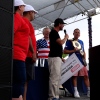 乔伊·切斯特纳特 (Joey Chestnut)(右)在赢得布利斯堡热狗比赛后手捧金腰带,而 Impossible Foods 首席执行官则在舞台上手捧一张巨额支票。