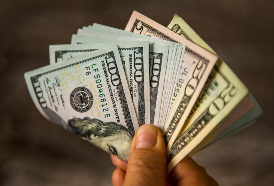 一只手拿着各种面额的现金。