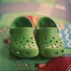 这张照片展示了一双绿色的 Crocs 鞋放在彩色地毯上。