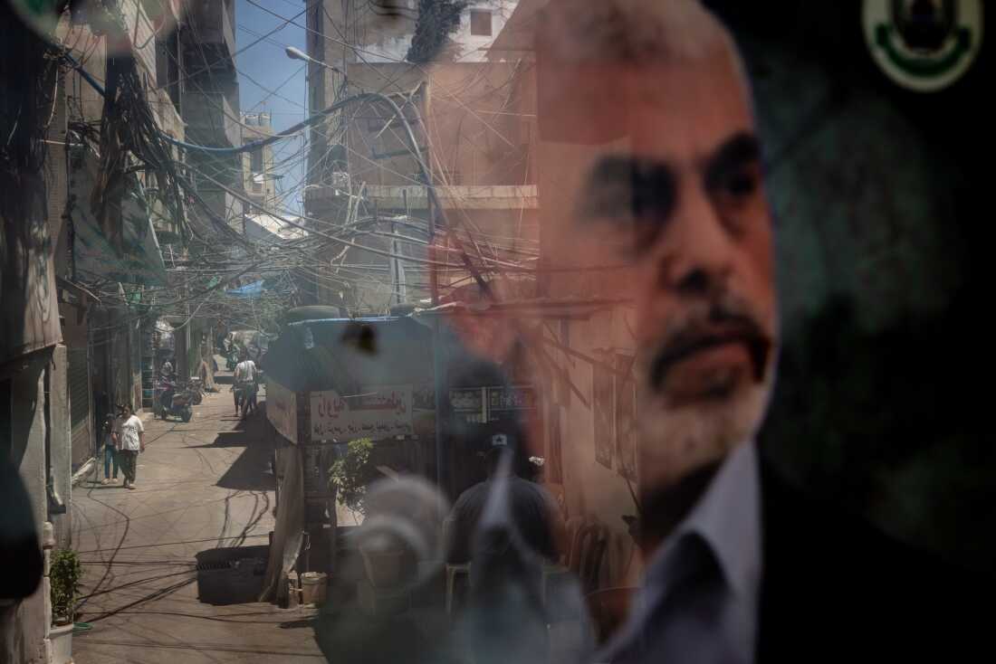 8 月 8 日,贝鲁特 Bourj al-Barajneh 巴勒斯坦难民营中,人们倒影在展示哈马斯领导人叶海亚·辛瓦尔 (Yahya Sinwar) 海报的窗户上。