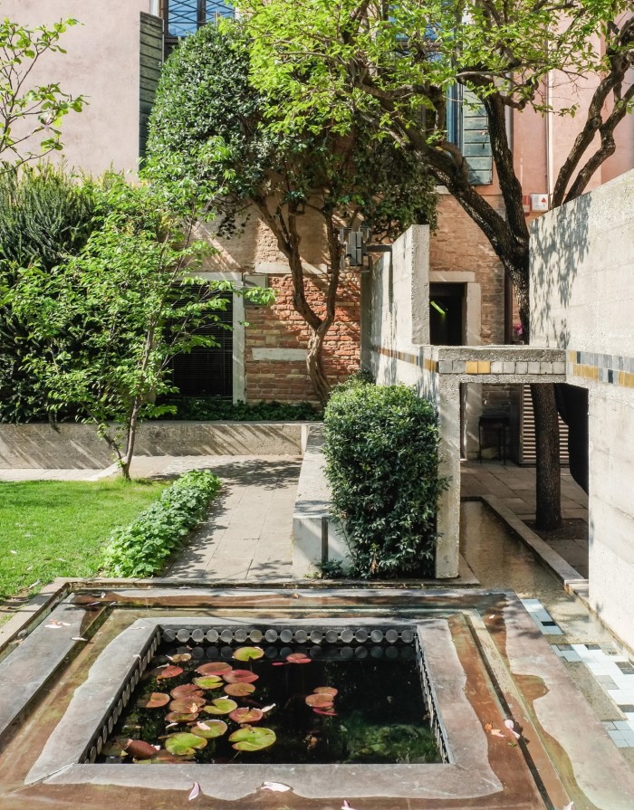 奎里尼·斯坦帕利亚基金会 (Fondazione Querini Stampalia) 花园中的池塘、小草坪和建筑师卡洛·斯卡帕 (Carlo Scarpa) 的现代主义石材细节