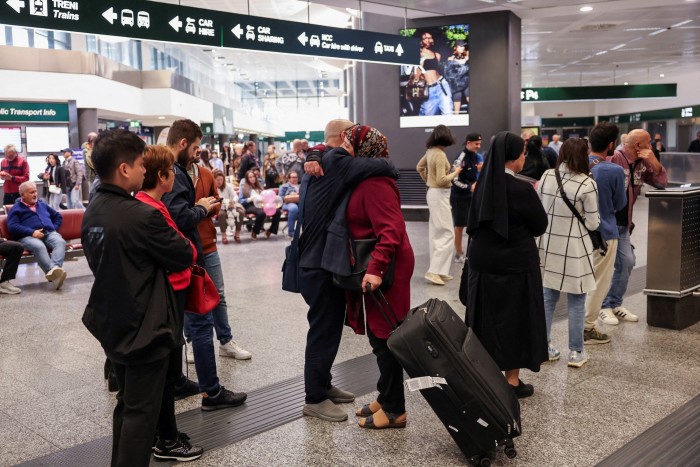 一名从贝鲁特抵达的乘客在意大利米兰马尔彭萨机场抵达航站楼内拥抱一个人